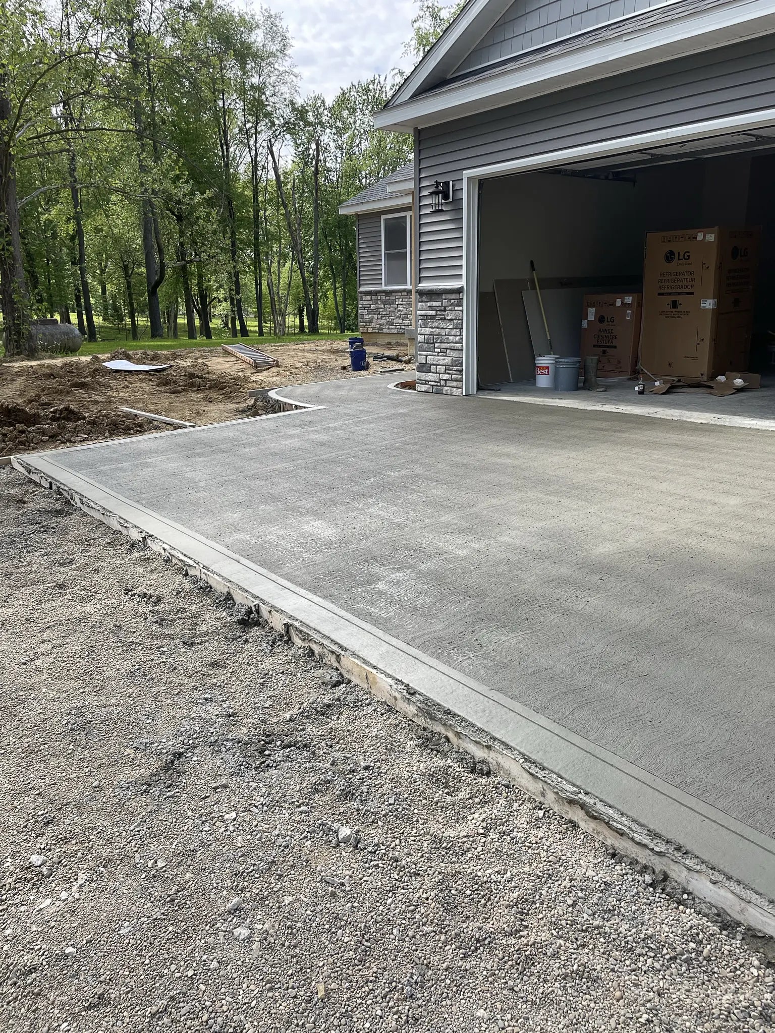 New concrete driveway extending from a garage with construction materials.