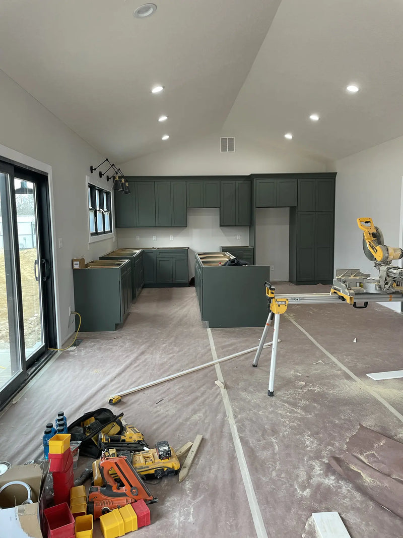 Kitchen under construction with gray cabinets and tools on the floor.