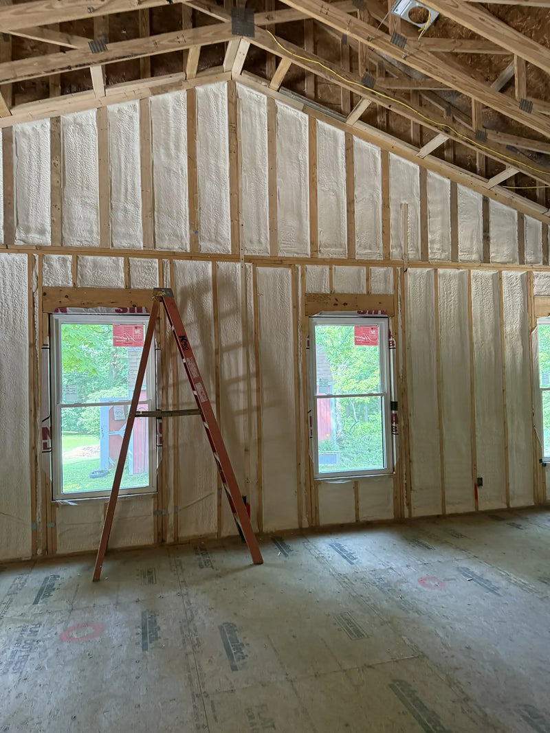 Under construction room with wooden framing and insulation, ladder leaning against a wall.