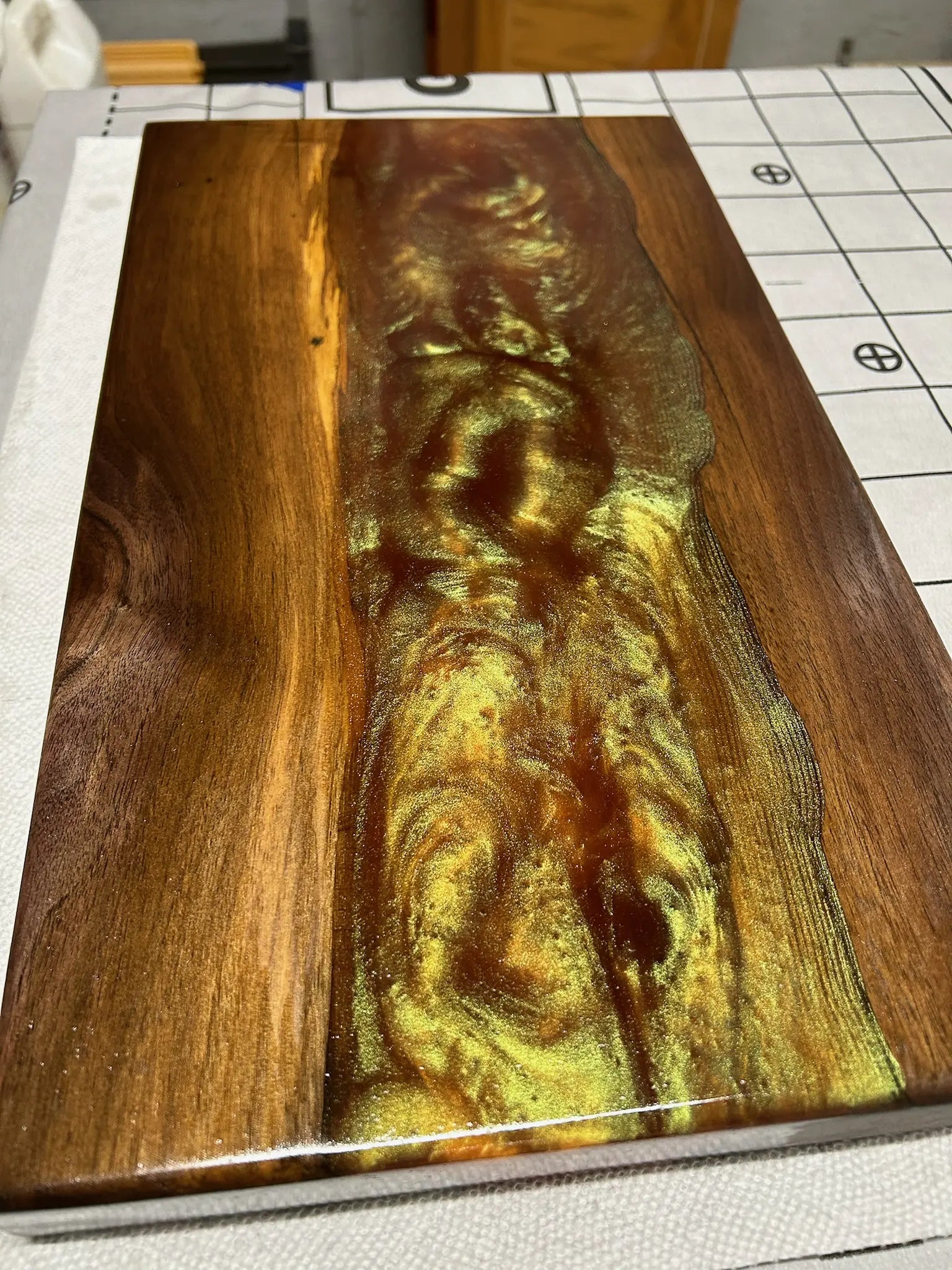 Wooden serving tray with a gold and brown resin design on a grid background