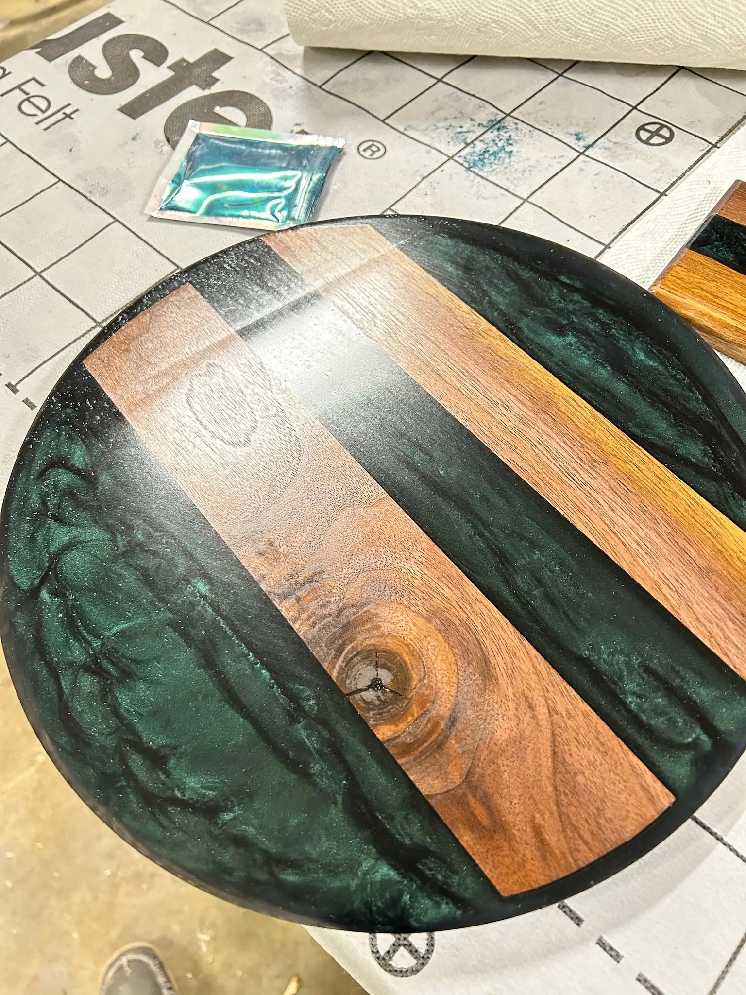Round wooden serving tray with green resin on a crafting surface