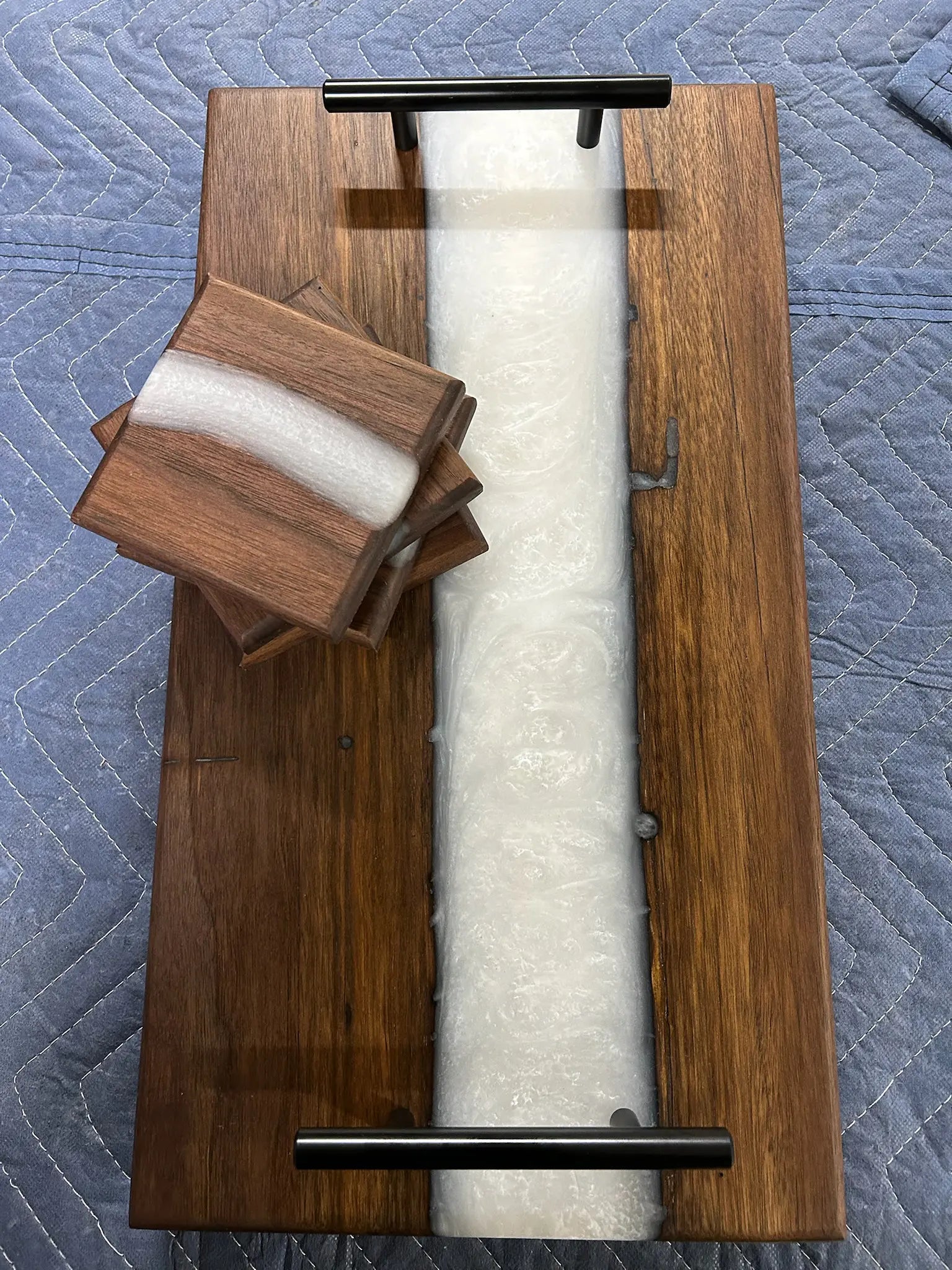 wooden walnut resin charcuterie board with coasters on top of a moving blanket