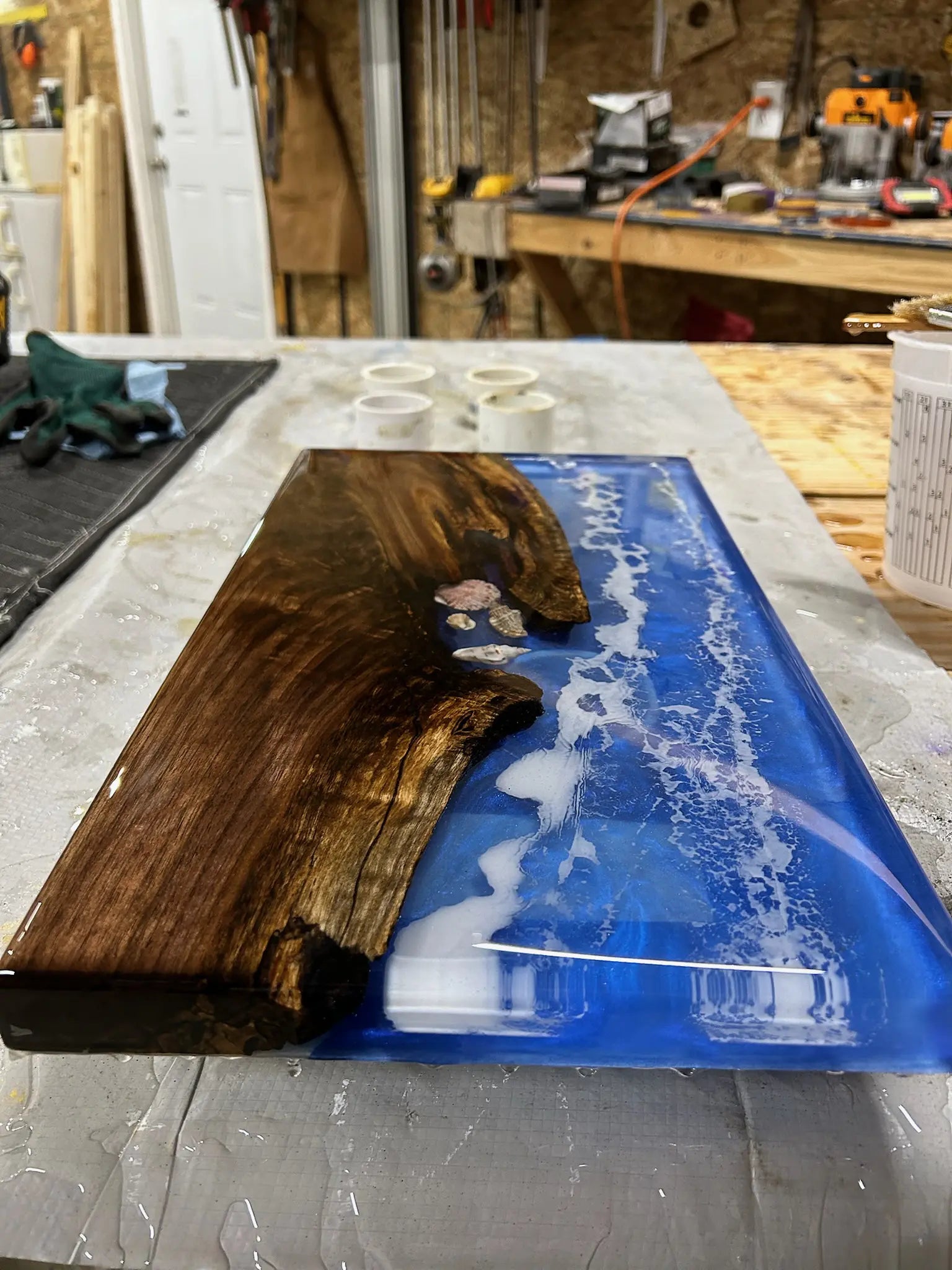 Wooden slab with blue ocean resin inlay on a workshop table