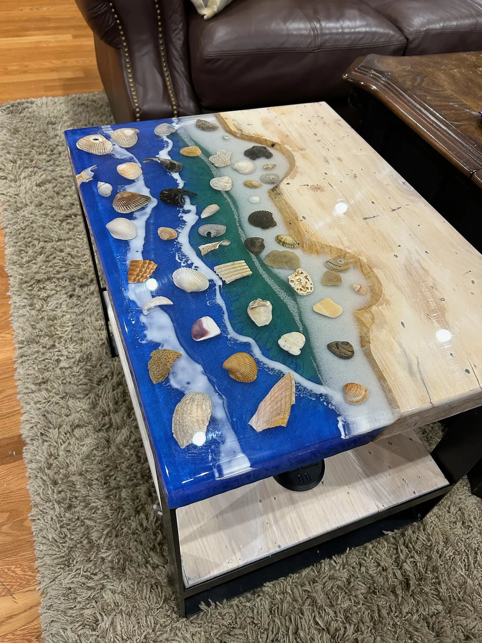 Ocean Resin Coffee table with a decorative surface featuring shells and stones in a living room setting.